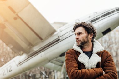 erkeksi ve kendinden emin, ceketli adamı ayakta dışında eski bir uçak ile bir pilot,