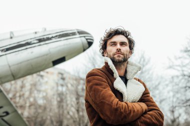 erkeksi ve kendinden emin, ceketli adamı ayakta dışında eski bir uçak ile bir pilot,