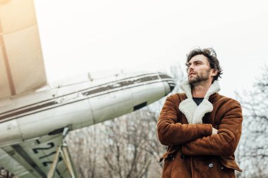 erkeksi ve kendinden emin, ceketli adamı ayakta dışında eski bir uçak ile bir pilot,