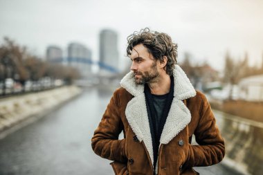 bir nehir yanında ayakta dışında ve hakkında bir şeyler düşünme veya içinbeklediğini sakal ve kış veya sonbahar kat yalnız yakışıklı adamla