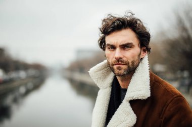 bir nehir yanında ayakta dışında ve hakkında bir şeyler düşünme veya içinbeklediğini sakal ve kış veya sonbahar kat yalnız yakışıklı adamla