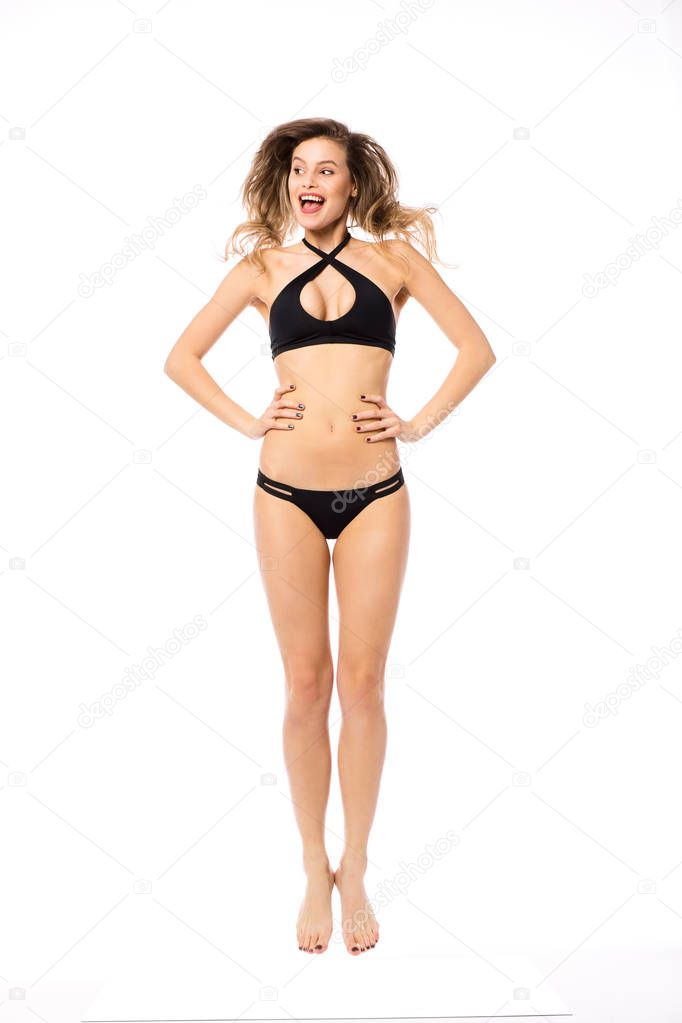 Studio shot of a young woman in a bikini isolated on white jumping with joy and big smile