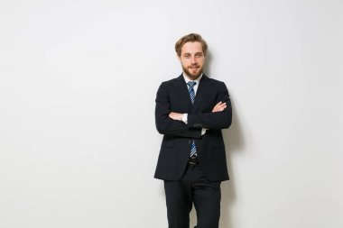 kamera için emin seyir emin zarif adam katlanmış silah karşı takım elbise ve kravat, beyaz bir duvar ile ayakta