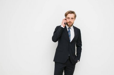 ciddi bir konuşma telefonda, giyen işadamı şık takım, sakallı, Olgun adam endişelendim biraz, kameraya bakarak beyaz bir duvar üzerinde