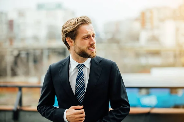 portrait of smiling handsome man, in elegant suit, successful businessman smiling outside, looking to side