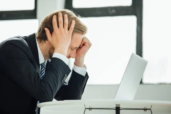 stock image business man in elegant costume looking very upset at laptop, disappointed with loss, with headache