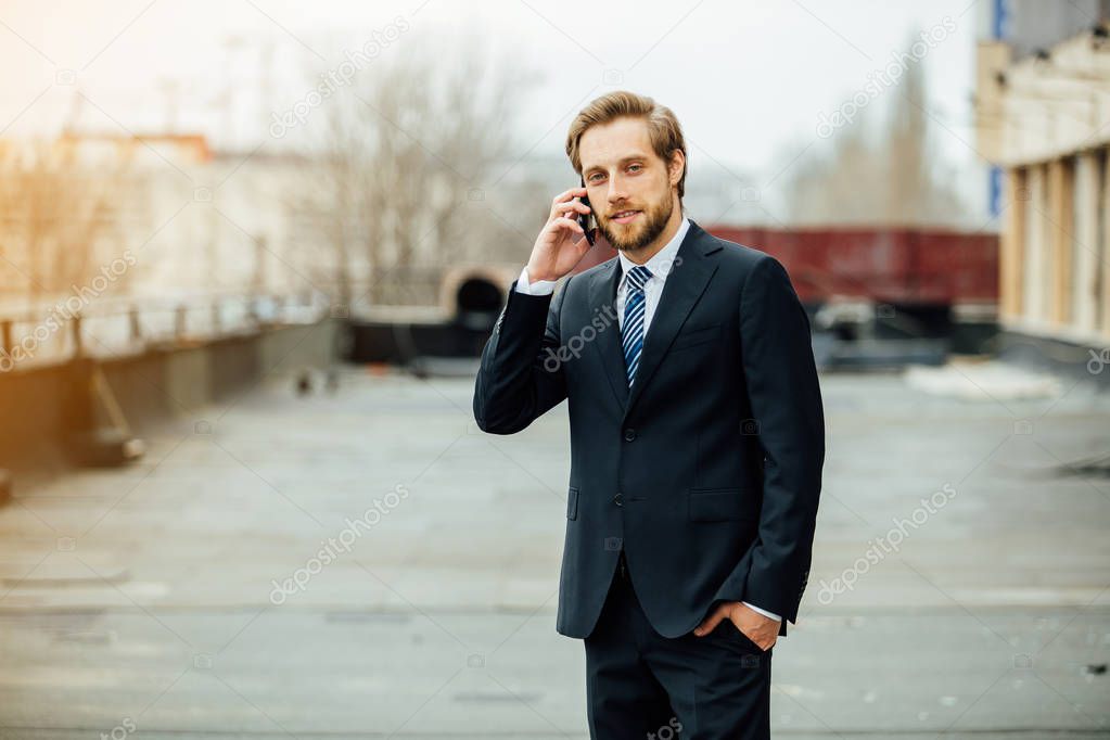 focused elegant businessman with cellphone outside