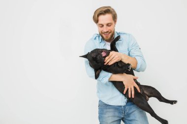sevgi ile onun kollarında köpeğini tutarak ve onunla, beyaz bir arka plan karşı oynayan genç ve güzel bir adam