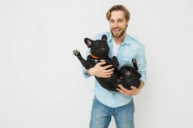 sevgi ile onun kollarında köpeğini tutarak ve onunla, beyaz bir arka plan karşı oynayan genç ve güzel bir adam