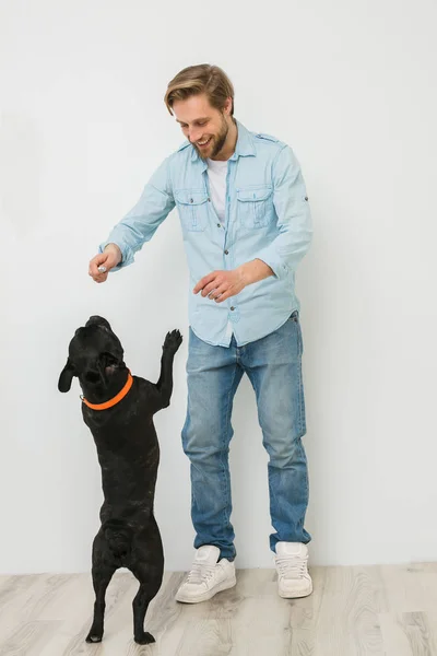 young blonde guy, handsome man, playing and loving his dog, on white background