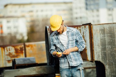 işe, bir yerde dışında bir paslı inşaat alanında, başlamak için hazır kontrol onun aracı işçisi kask ile araçlar, kafasına ile bir şal gömlekli sakallı güçlü bir adam