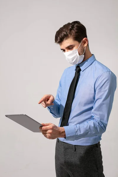elegant business man or medical stuff, working on a tablet with face mask for contagious virus