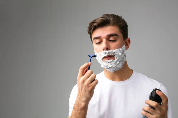 portrait with man with foam on face, thinking about his beard that is about to cut