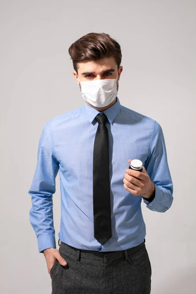 elegant man with tie and mouth protection taking some pills for stress or to prevent getting sick