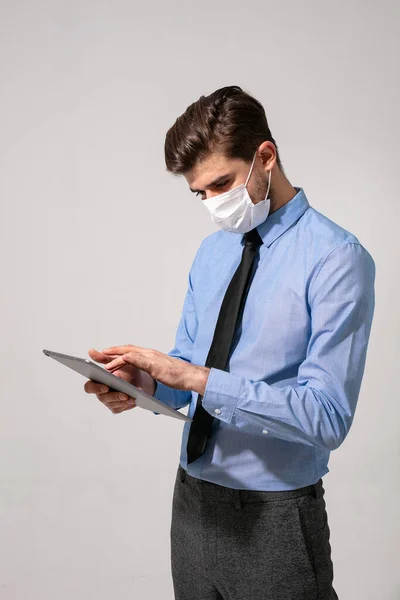 elegant business man or medical stuff, working on a tablet with face mask for contagious virus