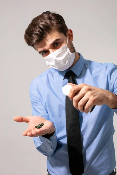 elegant man with tie and mouth protection taking some pills for stress or to prevent getting sick