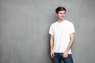 Gri arka plan beton duvarda duran normal bir genç adam.