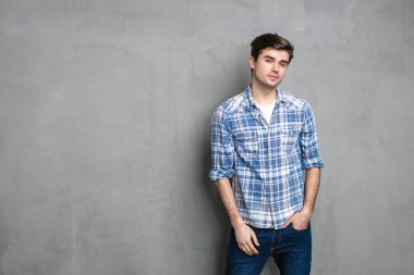 Endüstriyel beton duvarın karşısında duran kendine güvenen modern ve havalı adam