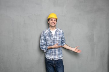Güvenlik kaskı takan kendine güvenen genç işçiler beton gri bir duvarda görüntünün boş bir tarafını mesaj olarak sunuyor ya da bir şeyleri teşvik ediyor.