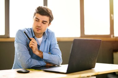 Genç adam dizüstü bilgisayarla çalışırken stresli zaman geçiriyor.