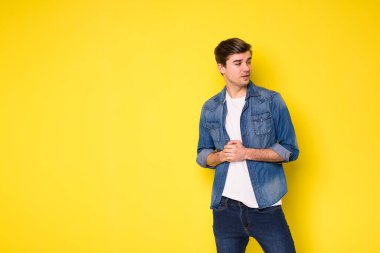 Sarı arka planda duran kot elbiseli yakışıklı genç adamlar.