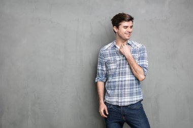 Görüntünün boş bir tarafına bakan sıradan görünümlü kendine güvenen bir adam, endüstriyel beton duvarda.