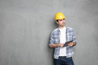 Harekete geçmeden önce düşünün, güvenlik kaskı ve modern tabletli genç işçiler sahip olduğu projeyi bitirmek için bir çözüm arıyorlar, beton duvarın üzerinde duruyorlar.