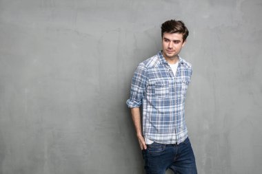 Görüntünün boş bir tarafına bakan sıradan görünümlü kendine güvenen bir adam, endüstriyel beton duvarda.