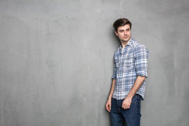 Endüstriyel beton duvarın karşısında duran kendine güvenen modern ve havalı adam