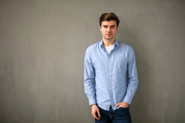 Endüstriyel beton duvarda duran genç girişimci, pozitif ve kendinden emin görünüyor