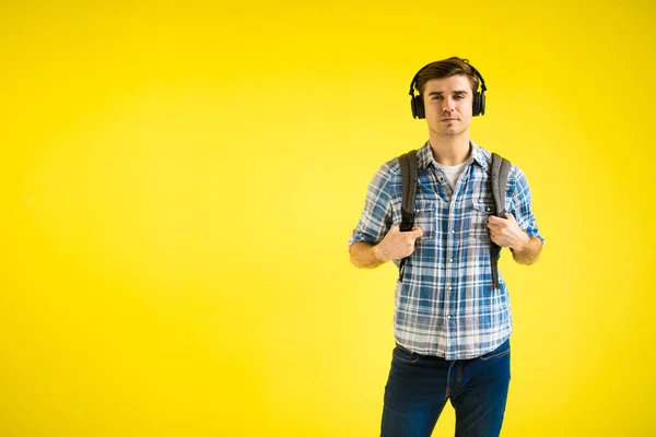 what is your outfit for work, young person with backpack and headphones on yellow background