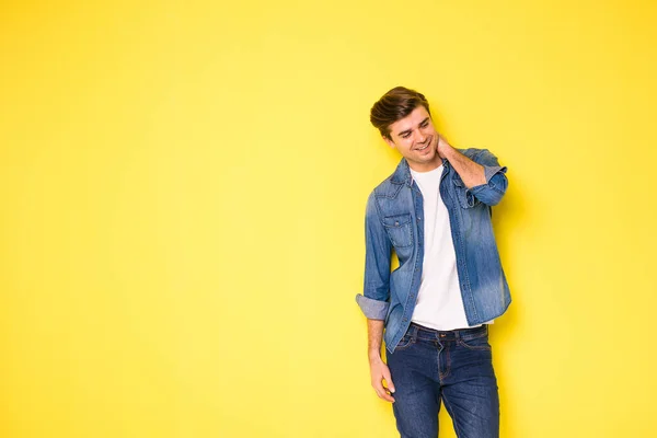 smiling optimistic person in cool jeans shirt standing on yellow background