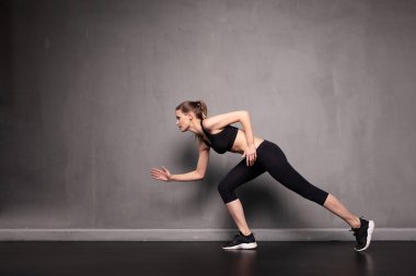 Genç atletik kadın gri endüstriyel duvarda spor yapıyor.