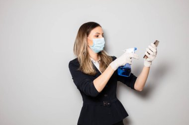 Kadın cep telefonunu dezenfektan bezle bakteriden temizliyor.