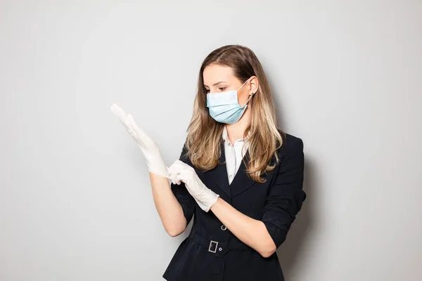 young elegant business woman wearing facial protection mask and fixing her gloves, this is the outbreak outfit work