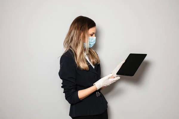 woman in formal office outfit and protection mask and gloves presenting a tablet to the camera