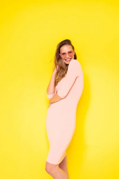若い現代の女性は 黄色の背景で喜びを持ってポーズをとったり ピンクのサングラスで夏の波を刺激したり — ストック写真