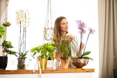 Genç bir kadın ev bitkileriyle ilgileniyor, bahçe işleriyle uğraşıyor. Kadınlar için ev aktivitesi