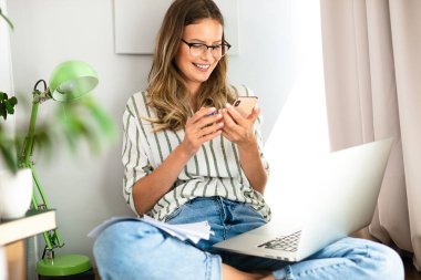 Kadın telefonuyla ya da internetle iletişim kurarken evde kalır, çalışır ya da ders çalışır.
