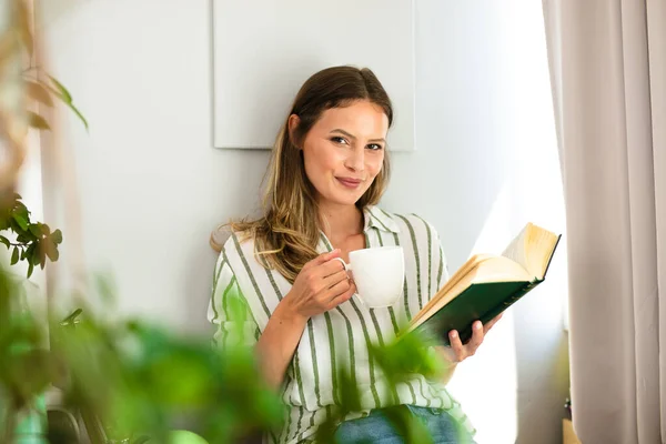 Mujer Leyendo Junto Una Ventana Luminosa Relajándose Tomando Café Relajándose — Foto de Stock