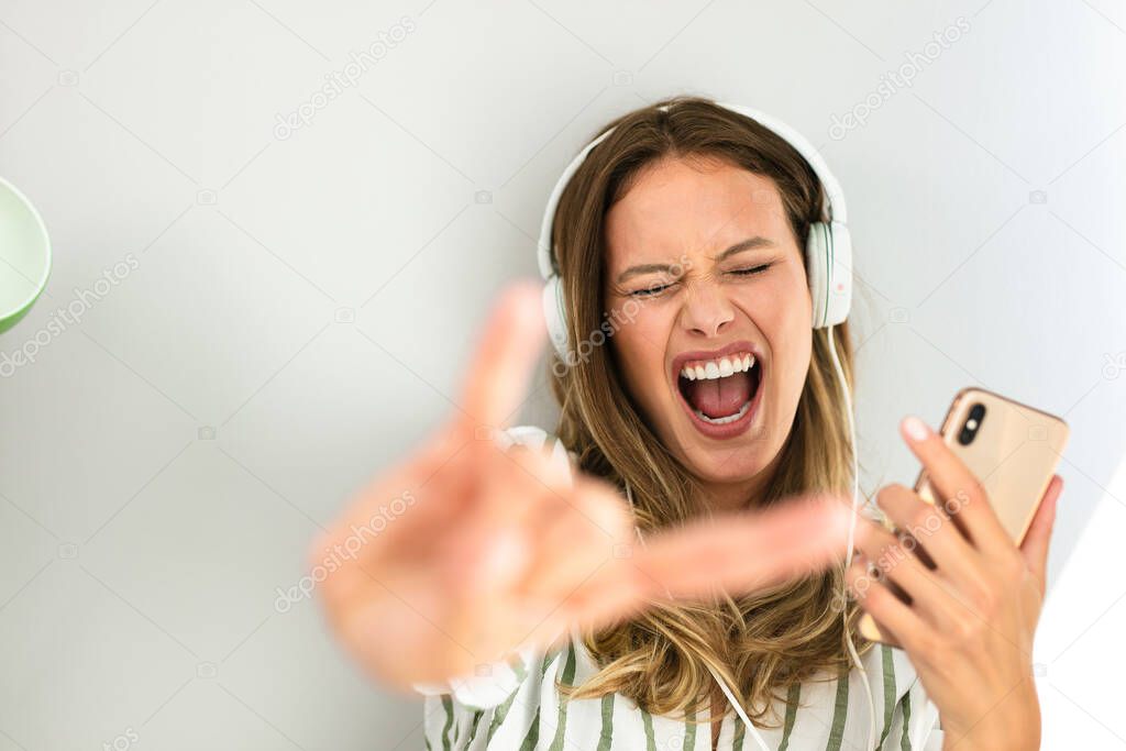 portrait of a happy woman with headsets listening music and and showing rock sign