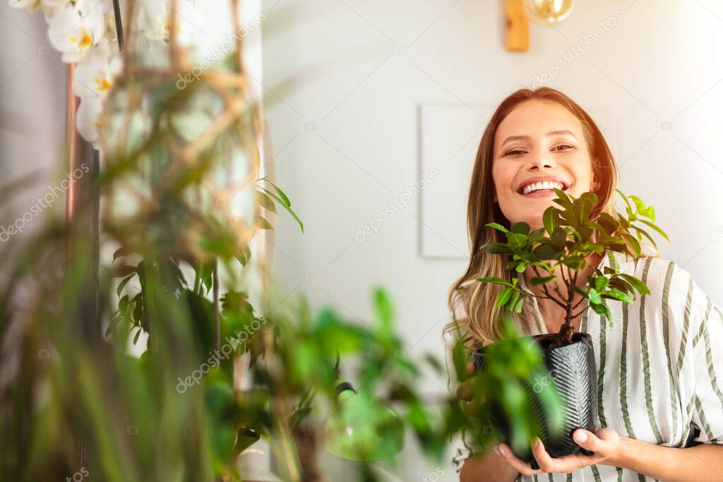 take care and love your house plants, young woman holding a bonsai in her arms with joy and love, home healthy activity