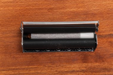 Ahşap arka plandaki makinede elle sarılmış sigara.