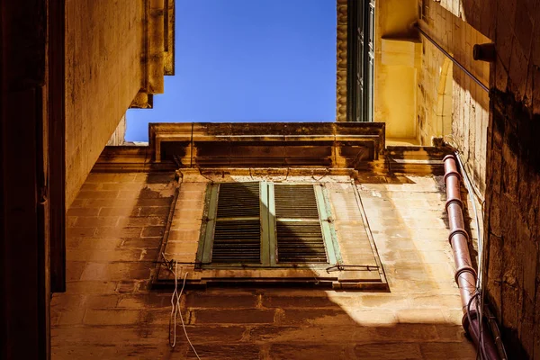 Старое окно закрыто ставнями с голубым небом на заднем плане — стоковое фото