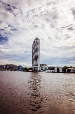 Arka planında bulutlu gökyüzü olan modern gökdelen