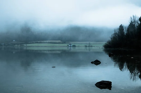 Nebliger Morgen am Rande des ruhigen Sees in den österreichischen Alpen — Stockfoto