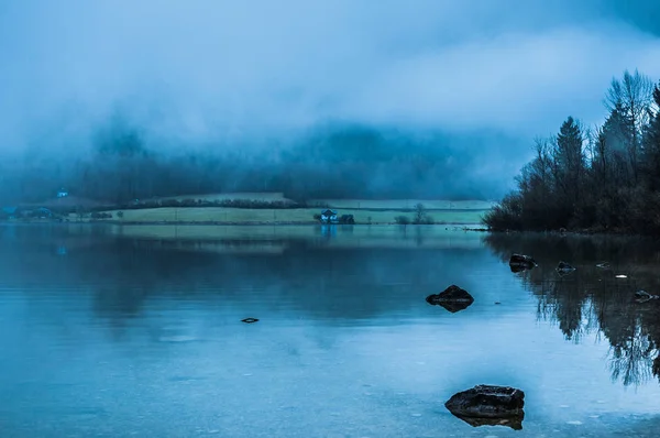 Nebliger Morgen am Rande des ruhigen Sees in den österreichischen Alpen — Stockfoto