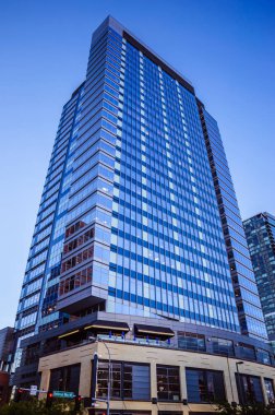 Akşamları arka planda açık mavi gökyüzü olan modern ofis binası.