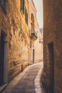 Gün batımında eski binaların arasında dar bir sokak.