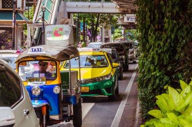 Bangkok, Thailand - July 11, 2015: Heavy traffic in Thailand capital, Bangkok downtown with cars, buses, taxis and people on the wide street surrounded with green trees